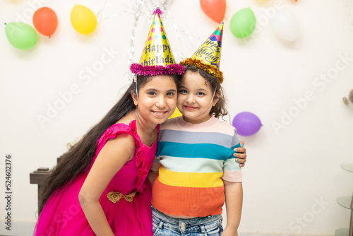 Portrait of smiling young Indian girls sisters making party and celebrating birthday together.