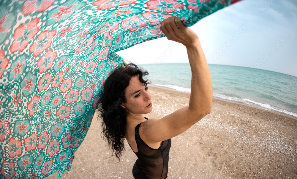 Fototapeta premium A woman holds a headscarf over her head and the wind blows her shawl