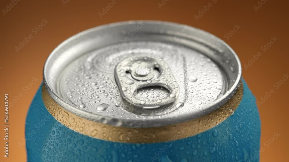 Cold Beer can with water drops closeup. Blue aluminium can with drinks on brown background