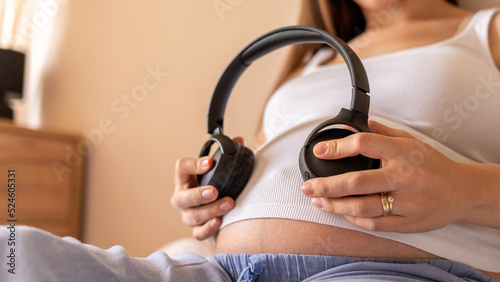 Pregnancy therapy music. Pregnant woman listening to music. Mother belly listen headphones sound. Pregnancy, medicine health care and people concept.