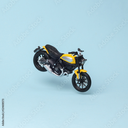 Miniature motorbike model flying in antigravity on blue background with shadow. Levitation object in the air. Creative minimal layout