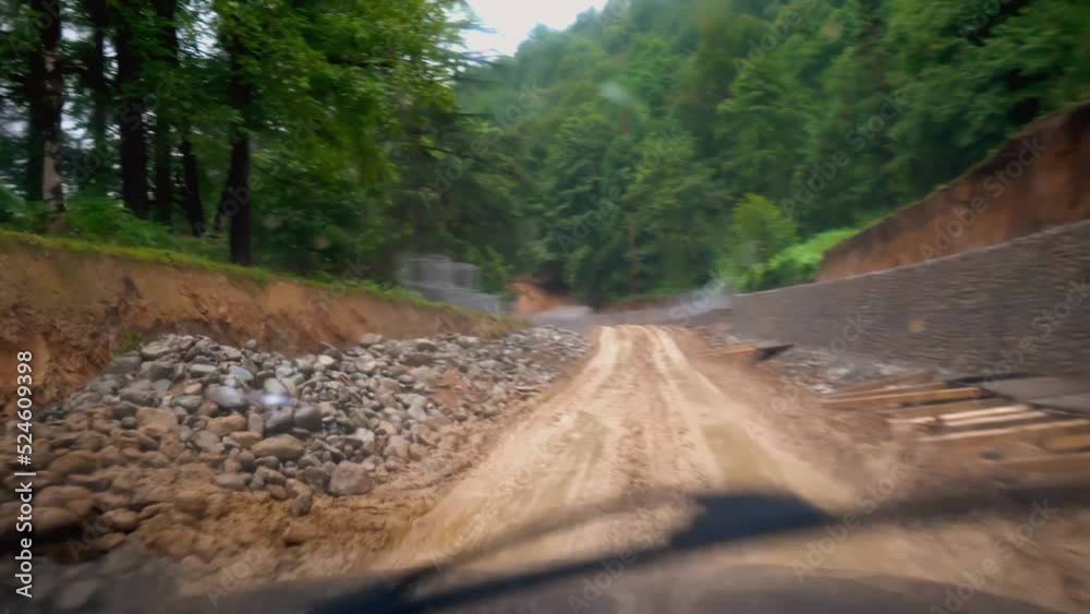 Car is moving along road washed out by rains, camera shoots inside from cabin. Mountain road of clay in rain. Impassable places. brushes clean window. Impassability. Car is moving along road washed out by rains, camera shoots inside from cabin. Mountain road of clay in rain. Impassable places. brushes clean window. Impassability.