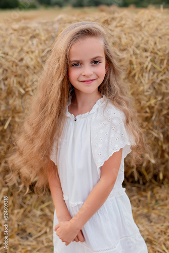 a girl with long hair and big eyes in a white dress in a wheat field