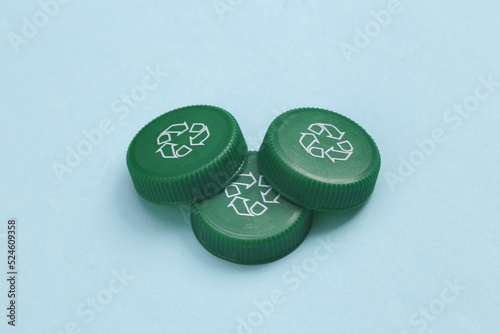Plastic bottle caps with recycle symbol on blue background. Eco concept