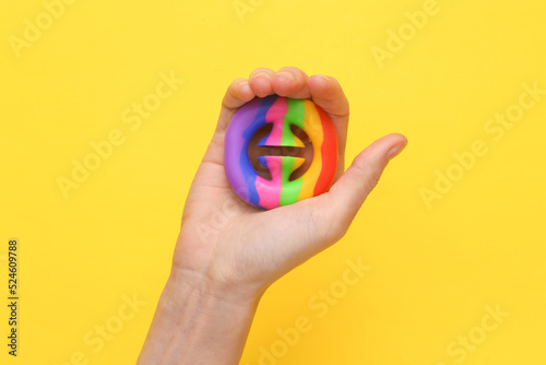 Hand squeezing antistress toy on yellow background