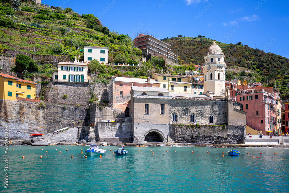 View on bay of water with moored boats and typical colorful houses in small village, Riviera di Levante, Vernazza, Cinque Terre, Italy