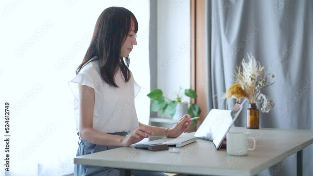部屋でタブレットPCを操作する若い女性 部屋でタブレットPCを操作する若い女性