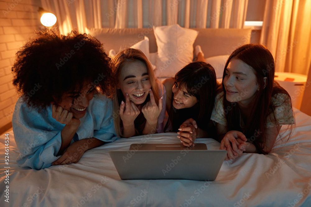 Girlfriends enjoying while watching laptop on bed