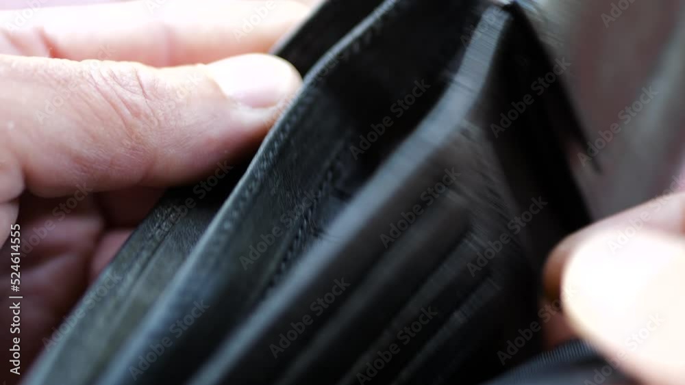 Caucasian man opens hes empty black synthetic leather wallet on harsh sunlight during a big economical crises. Caucasian man opens hes empty black synthetic leather wallet on harsh sunlight during a big economical crises.