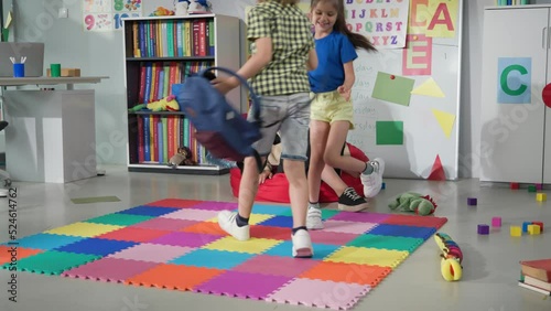 Primary school teacher greeting kids running into classroom