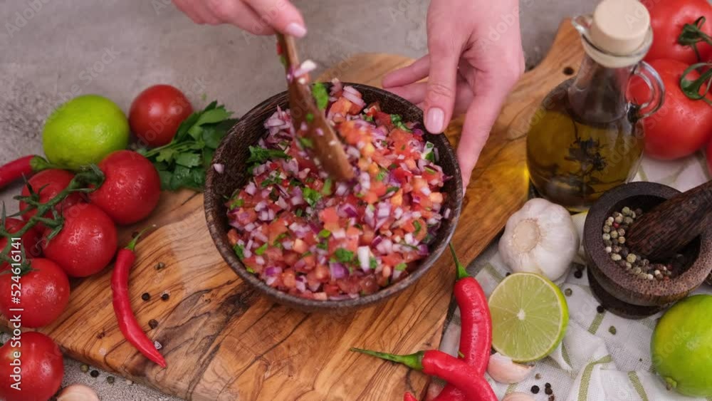 Slow motion shot of woman mixing salsa dip sauce ingredients in wooden bowl Slow motion shot of woman mixing salsa dip sauce ingredients in wooden bowl