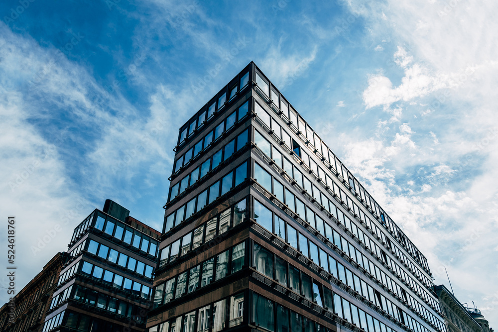 Part of a building with modern architecture, many windows and dark colors against a blue sky