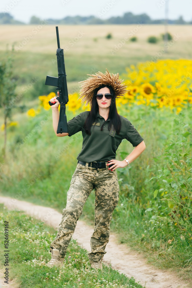 Female soldier in military uniform. A girl in a military uniform with a weapon. Ukrainian woman in a wreath