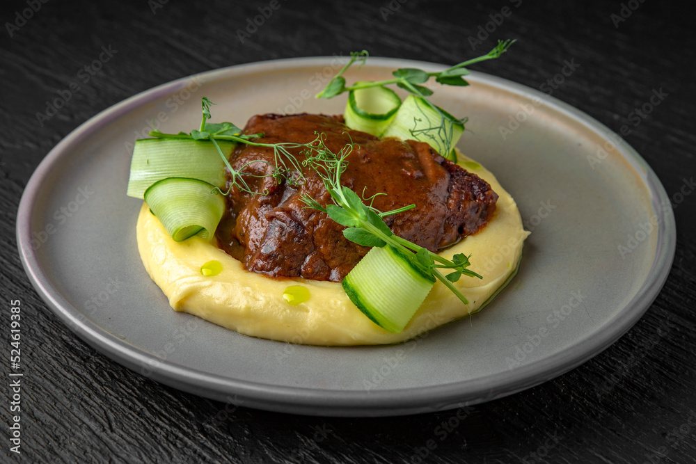 Airy mashed potatoes with liver in sauce in a ceramic plate on a dark textured background. Restaurant menu Isolated on black Airy mashed potatoes with liver in sauce in a ceramic plate on a dark textured background. Restaurant menu Isolated on black