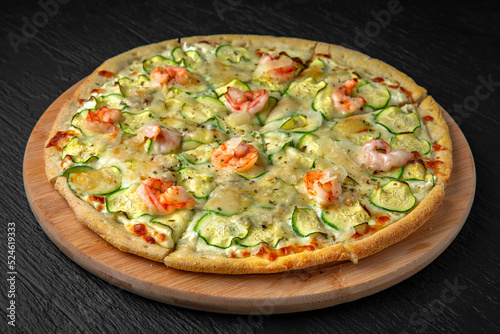 Pizza with zucchini, shrimp and Gorgonzola in a ceramic plate on a dark textured background. Restaurant menu Isolated on black
