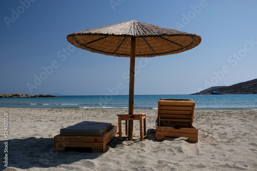 Fototapeta Naklejka Na Ścianę i Meble -  Two sunbeds and a sun umbrella at the amazing beach of Manganari  in Ios Greece
