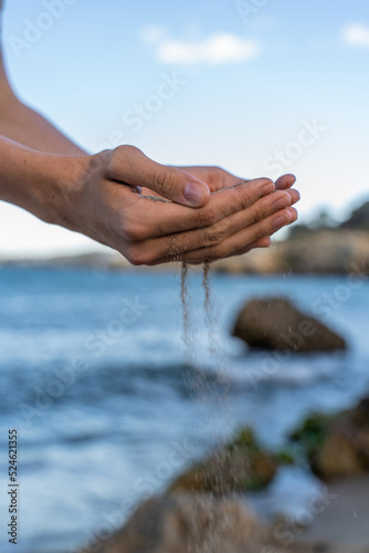 Hands of young man throwing sand through fingers at beach 