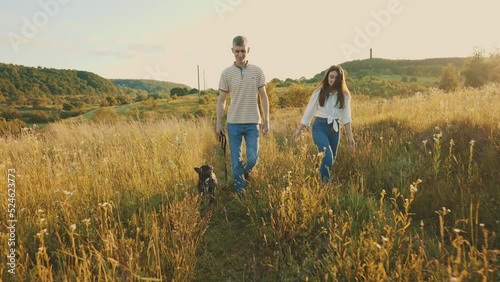4k slow motion shot of young happy couple having fun with their french bulldog outdoors in the countryside during beautiful sunset