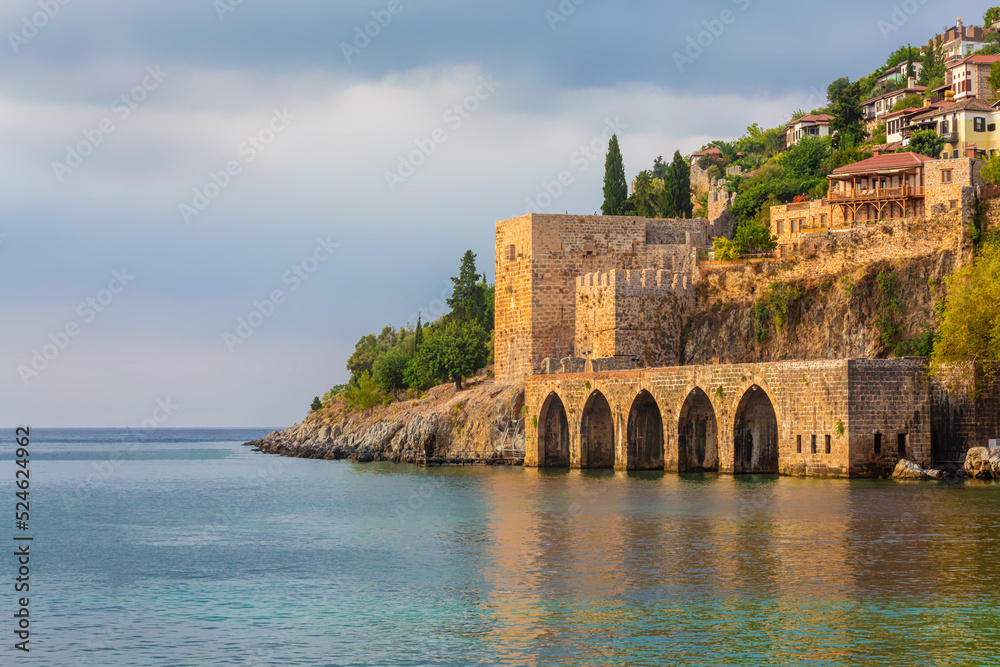 Ancient shipyard (Tersane) near of Kizil Kule tower in Alanya, Turkey (Turkiye) Famous tourist destination with high mountains. Part of medieval fortress (Alanya Castle) on the mountainside