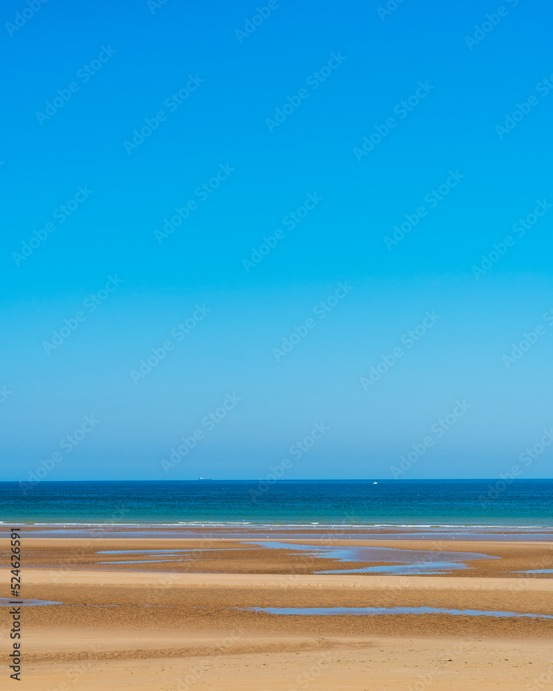 View of sand of beach with ocean and clear sky in background