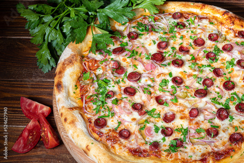Pizza with bacon and cheese, herbs and cherry tomatoes. With mozzarella, shrimp and octopus, mussels and other products on a wooden background.