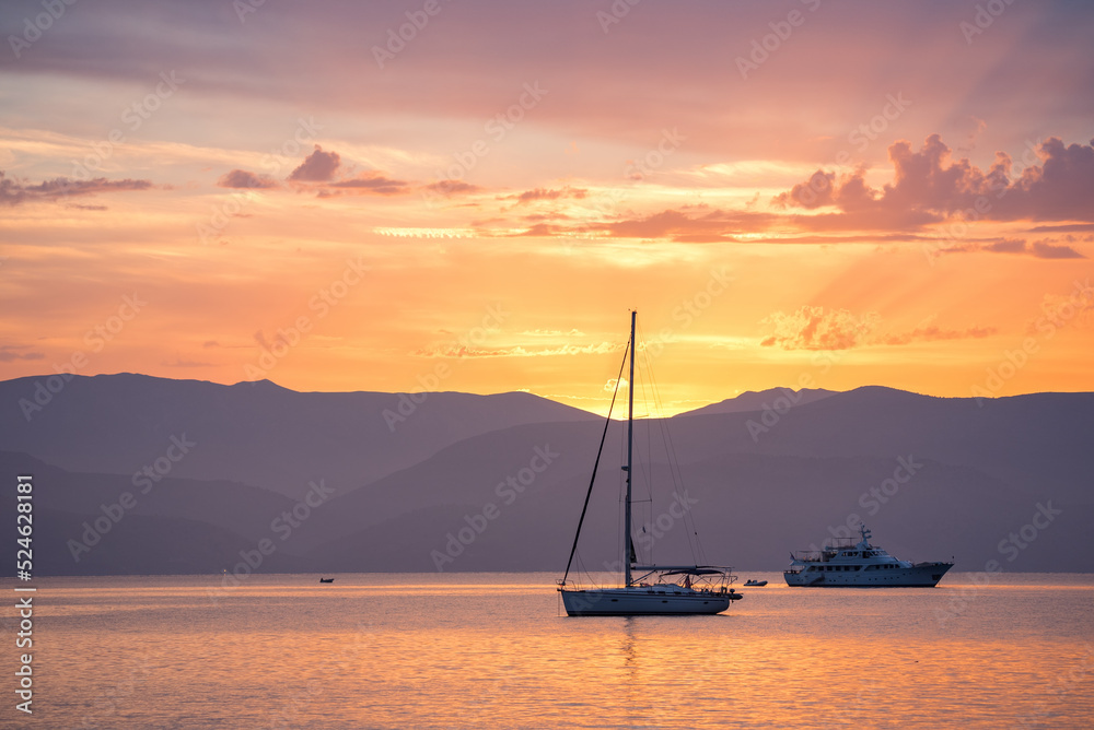 Bright sunset seascape with a sailboat and a ship