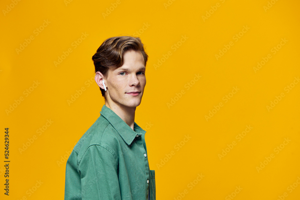 a guy in wireless headphones stands on a yellow background a guy in wireless headphones stands on a yellow background