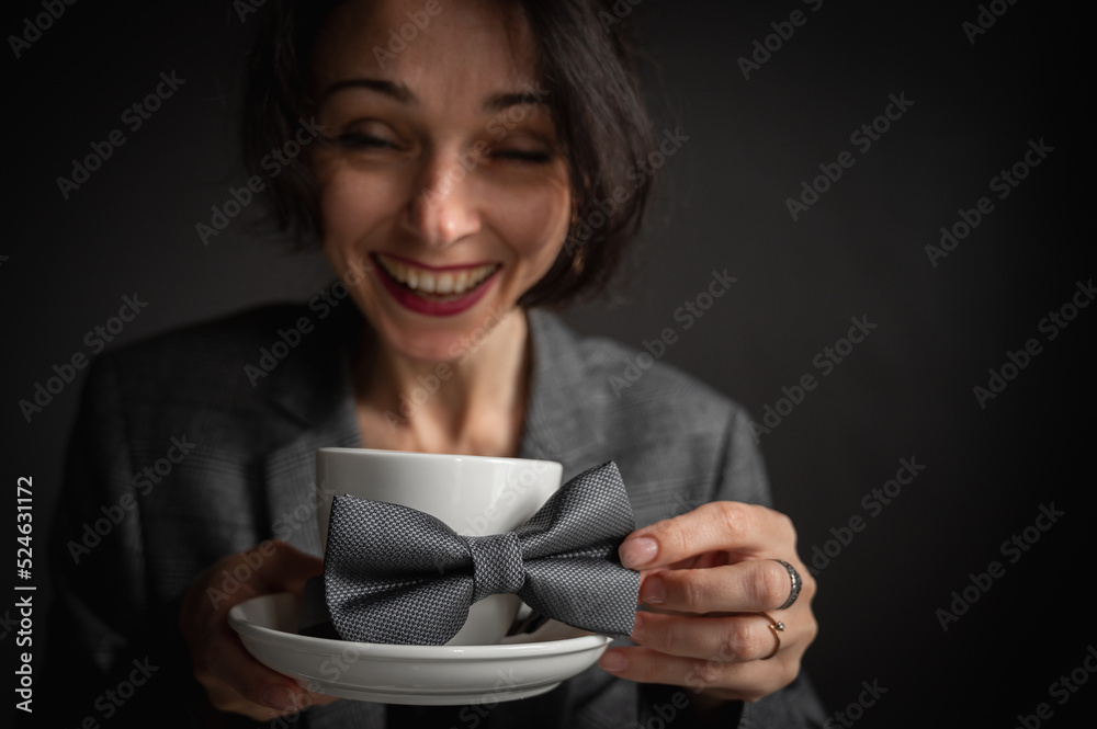 A young pretty, emotional girl shows facial expressions, surprise, drinks early coffee on a gray background, thoughtful, cheerful, a male butterfly on a white mug. Selective focus, low key A young pretty, emotional girl shows facial expressions, surprise, drinks early coffee on a gray background, thoughtful, cheerful, a male butterfly on a white mug. Selective focus, low key