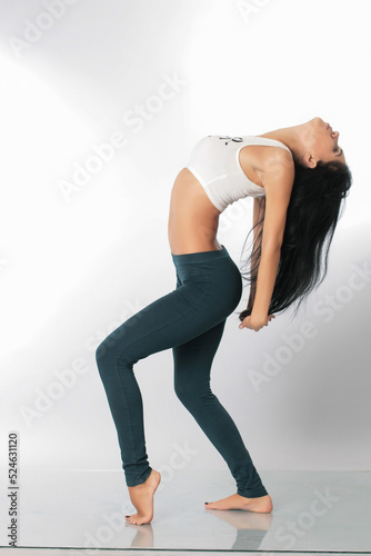 a pretty girl brunette stretching instructor, yoga, trainer, danser, posing in the studio on a white background in lasins and T-shirt photo