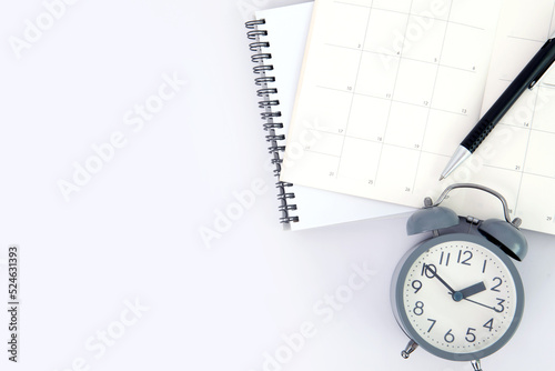 pen with white spiral notepad  and alarm clock calendar , business meeting agenda schedule, travel planning booking or project event milestone and reminder a yearly plan concept.