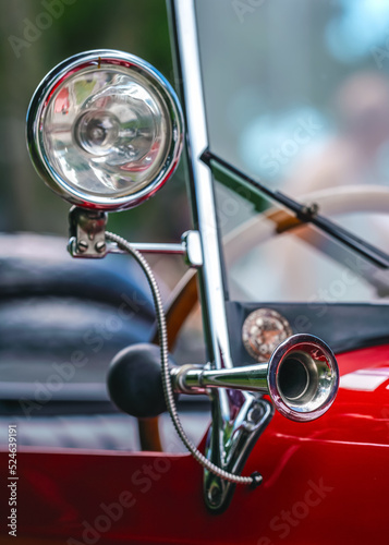 Shiny steel horn on red vintage car, closeup detail, only metal rim in focus
