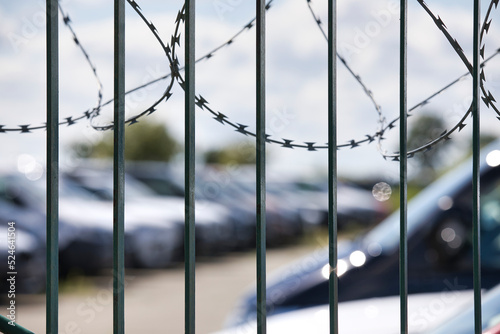 Stacheldrahtzaun umzäunt zur Sicherheit ein Parkplatz mit neuen Autos