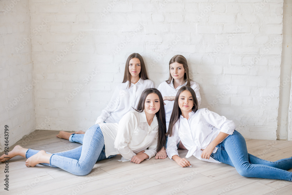 Pretty teenage girls models in trendy jeans and white shirts in the studio against the background of a white brick wall. Teenage fashion. beauty and fashion Pretty teenage girls models in trendy jeans and white shirts in the studio against the background of a white brick wall. Teenage fashion. beauty and fashion