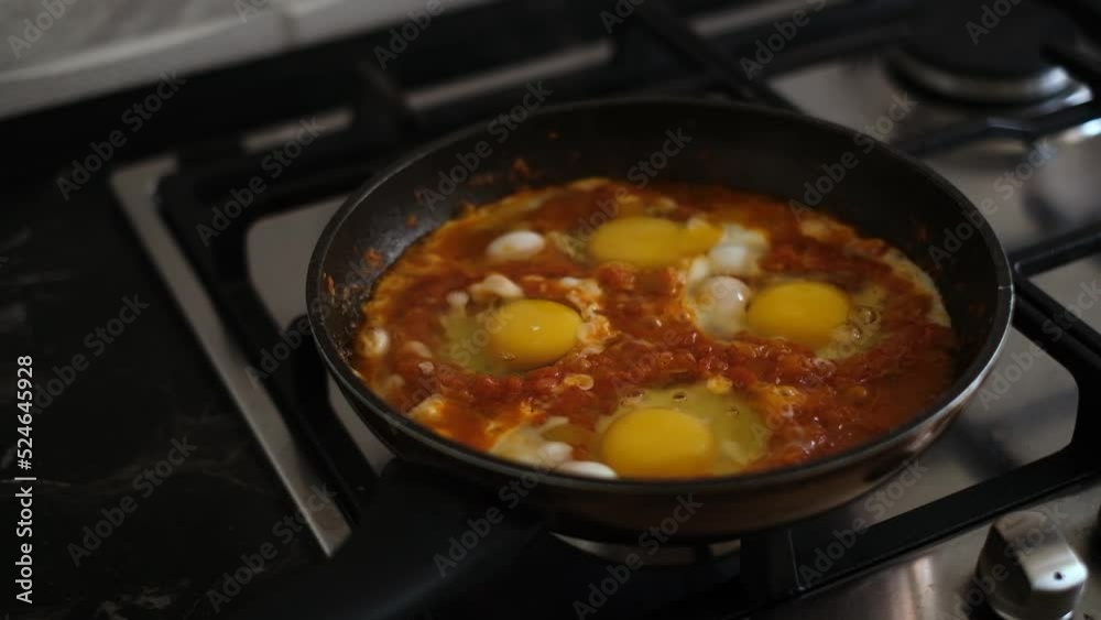 shakshuka is cooked in a frying pan on the stove close-up. fried eggs with vegetables in a pan
