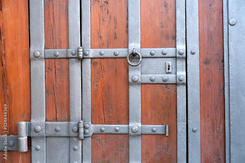 Detail of an old ancient castle wooden door with a beautiful iron knock handle. Close up.