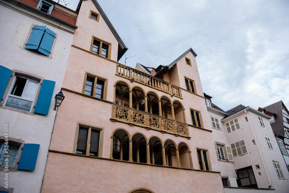 Obraz premium Colmar, Alsace, France, 4 July 2022: town capital of Alsatian wine, narrow picturesque street with medieval colorful houses, Timber framing or post-and-beam construction, carved stone arches