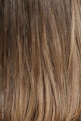 Hair coloring women close up texture background. Bunch of shiny straight blond hair in a wavy curved style. Copy space.
