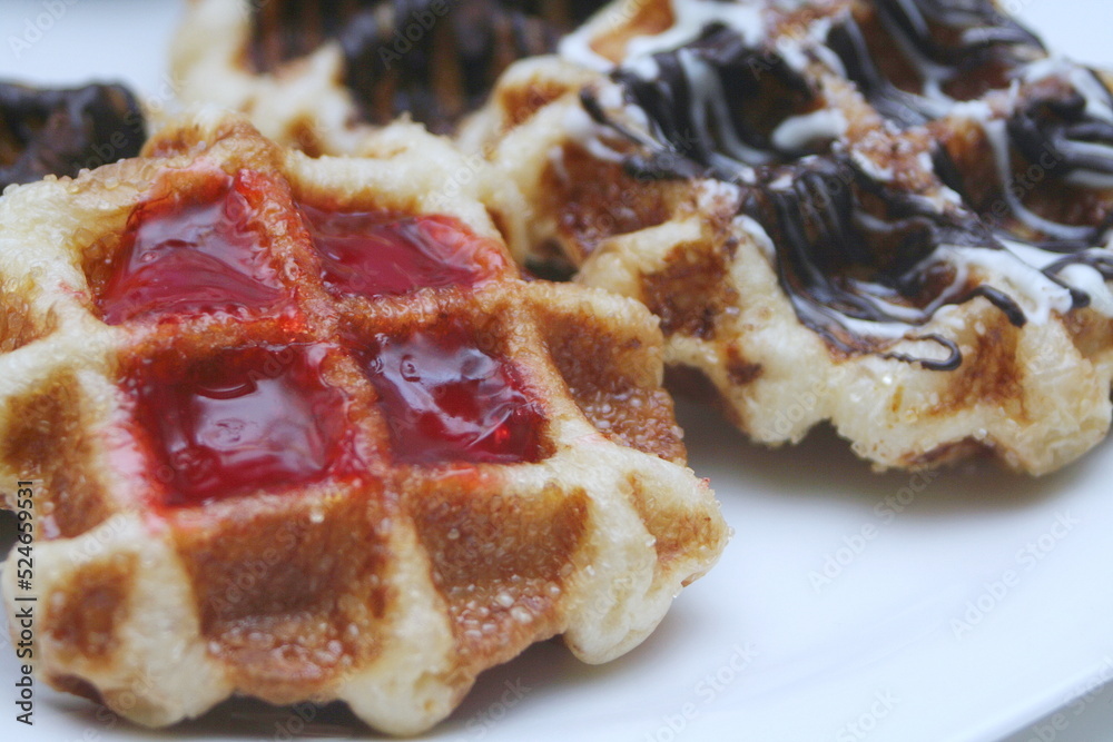 Waffles topped with chocolate and strawberries served in a white plate. Waffles topped with chocolate and strawberries served in a white plate.