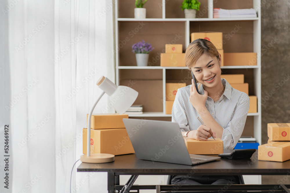 New business owner Asian woman working at home office Packaging on background SME entrepreneur online shopping or freelance work concept Young woman happy after new order from customer New business owner Asian woman working at home office Packaging on background SME entrepreneur online shopping or freelance work concept Young woman happy after new order from customer