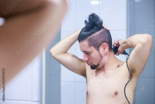 鏡に映る髪の毛をセルフカットする男性