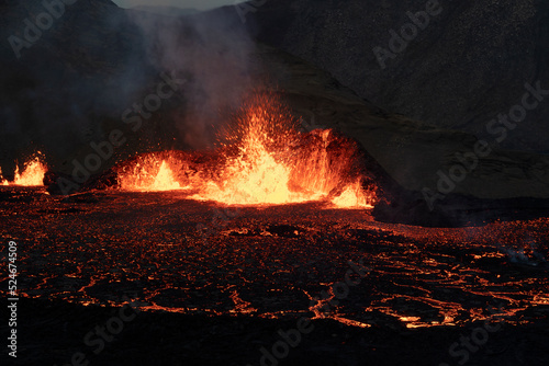 Volcano eruption at Meradalir near Fagradalsfjall, Iceland. Erupting magma and flowing lava at night.