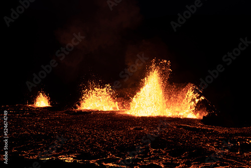 Volcano eruption at Meradalir near Fagradalsfjall, Iceland. Erupting magma and flowing lava at night.