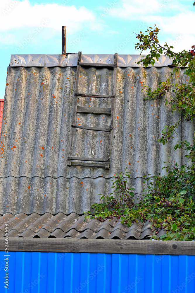 A fragment of a roof made of old asbestos cement sheets on a summer day A fragment of a roof made of old asbestos cement sheets on a summer day