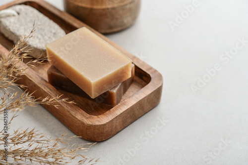 Natural soap bars and pumice stone on wooden tray