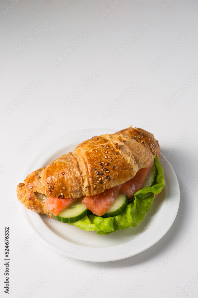 Croissant with salmon and cucumber on a white plate Croissant with salmon and cucumber on a white plate