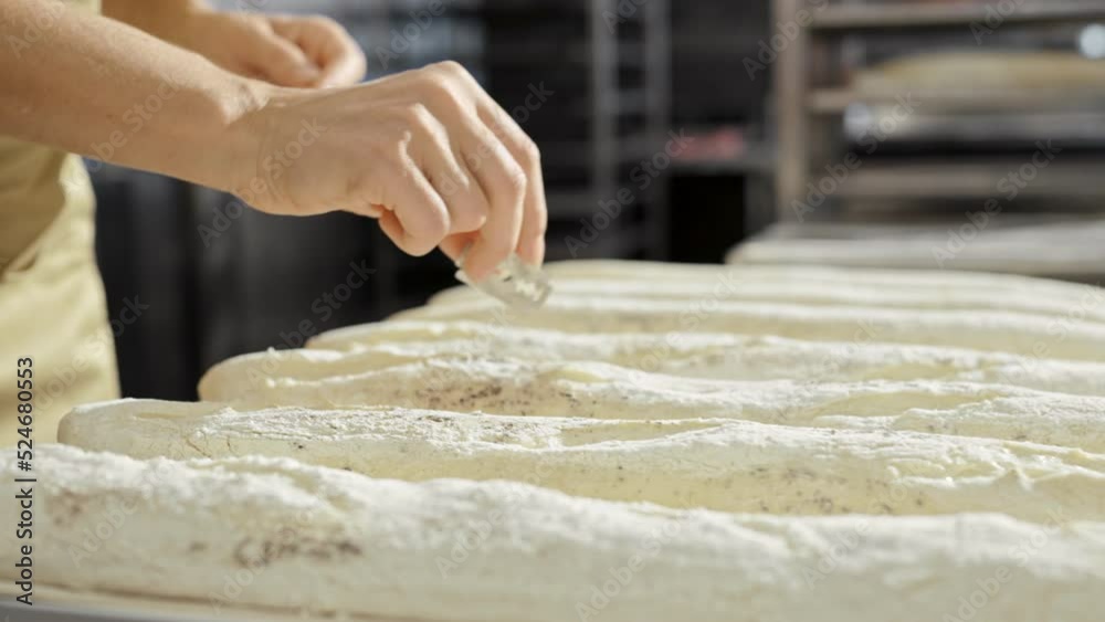 Close up of Caucasian female hand cutting dough with razor while working in bakery. Indoor. Work of baker concept. Woman preparing duff for pastry or bread and making shapes with shaver. Close up of Caucasian female hand cutting dough with razor while working in bakery. Indoor. Work of baker concept. Woman preparing duff for pastry or bread and making shapes with shaver.