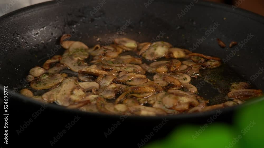 Close up of cream is poured into pan with mushrooms. Kitchen spatula stirs champignons in frying pan on stove. Cooking food Close up of cream is poured into pan with mushrooms. Kitchen spatula stirs champignons in frying pan on stove. Cooking food
