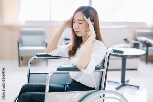 A young woman patient sits in a wheelchair in a clinic with a worried expression.