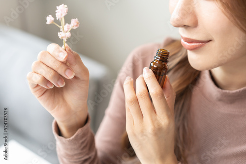 Aromatherapy, asian young woman, girl hand holding flower, bottle of essential perfume oil, enjoying smell fragrance of herbal from medicine natural organic at home.Therapy treatment, beauty skin care photo