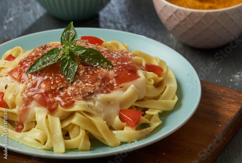 Tagliatelle Spaghetti pasta in tomato sauce on a turquoise wooden plate and black base. Italian food